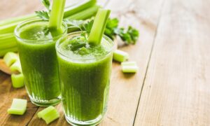 2 szklanki zawierające sok z selera naciowego stojące na drewnianym stole